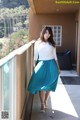 A woman standing on a balcony wearing a blue skirt.