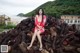 A woman in a red dress sitting on a pile of logs.