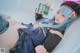 A woman with blue hair laying in a bathtub holding a book.