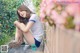 A woman sitting on the ground next to a fence.