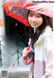 A woman holding a red umbrella in the rain.