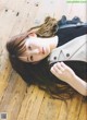 A woman laying on a wooden floor with her hair blowing in the wind.