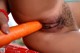 A woman is holding a carrot in her mouth.