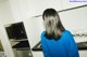 A woman standing in a kitchen looking at a microwave.